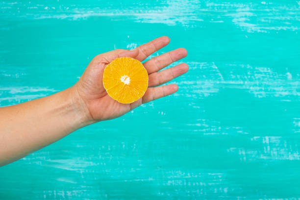 istock orange fruit in hand on color background. 969353284