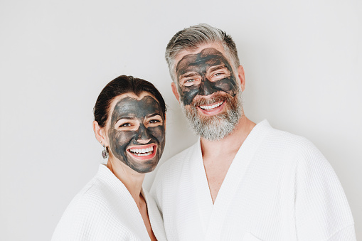 Happy couple wearing a charcoal mask