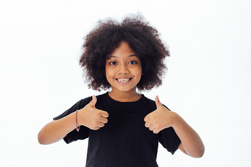 Adorable y alegre niño americano africano con afro peinado dando pulgares aislada sobre fondo blanco photo