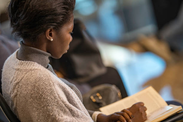 istock African-American woman reading a book while waiting for airplane 969396764