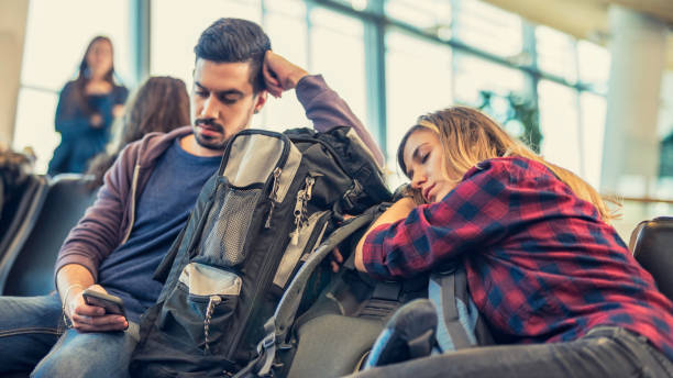 pareja adulto joven esperando en un pasillo del aeropuerto - airport waiting room waiting airport lounge fotografías e imágenes de stock