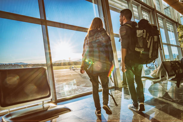 istock Backpacker couple looking through airport window 969402540