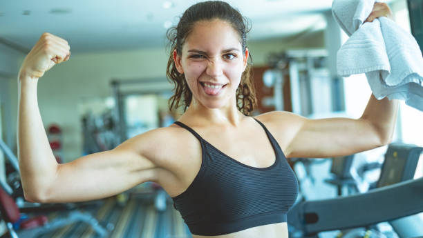 istock Woman flexing her muscles in gym 969412272