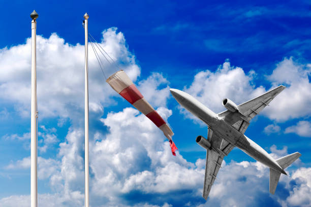 istock Airplane takes off in a beautiful summer sky with red and white windsock 969427938