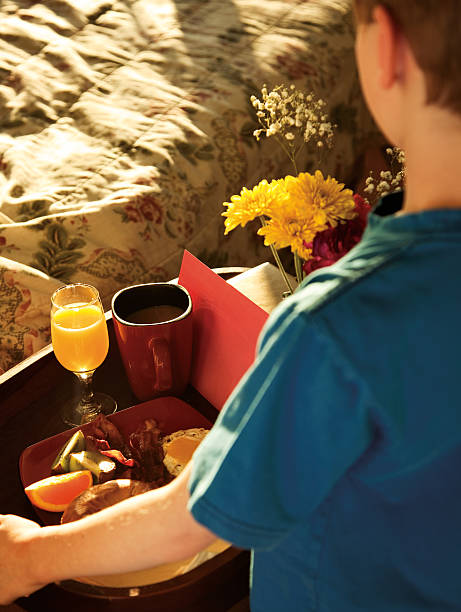 Boy bringing a tray full of food for breakfast in bed stock photo