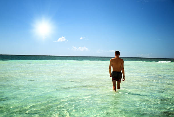 istock young man walking in Caribbean sea 96943296