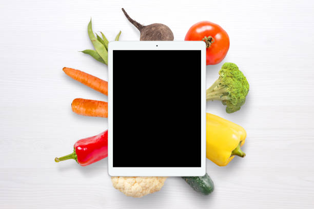 istock Blank tablet for mockup. Vegetables in background on white wooden table. 969435306