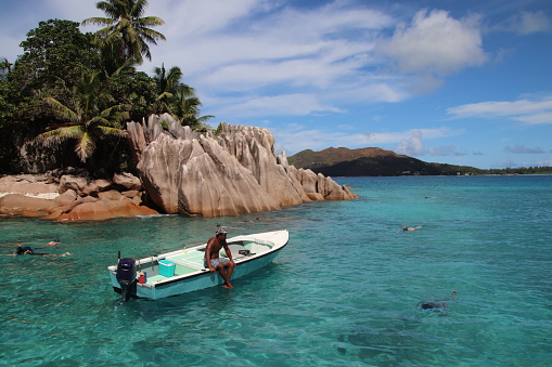 People enjoy visiting St. Pierre Island for snorkling. A tour guide is sitting in his tour boat. The small island is situated close to Praslin Island, Seychelles. The Indian Ocean has clear water and the island has a beautiful scenery with large red granite rocks.