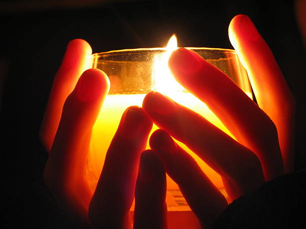 holding a candle in darkness stock photo