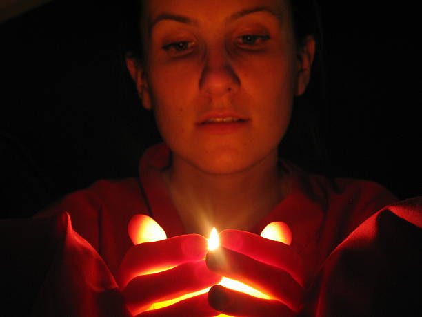 holding a light and watching flame of a candle stock photo