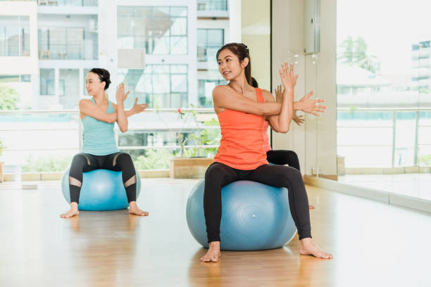 istock Yoga class in studio room,Group of people doing yoga pose with training ball, stretching pose,Wellness and Healthy Lifestyle. 969438462