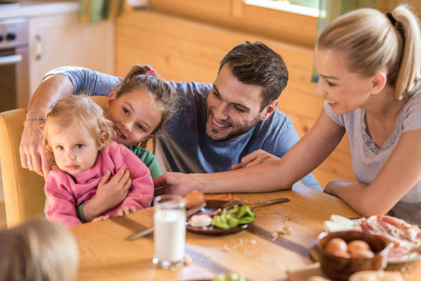 istock Young happy parents having breakfast with their small daughters at home. 969441534