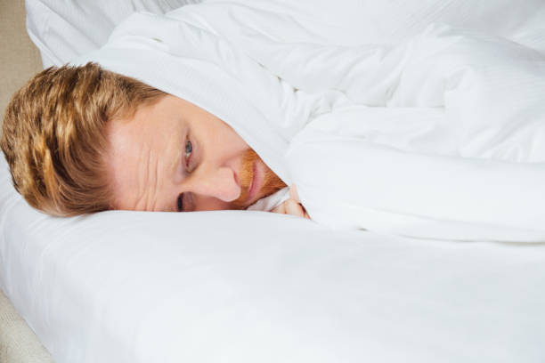 istock Man with fever wrapped in sheets in bed 969442170