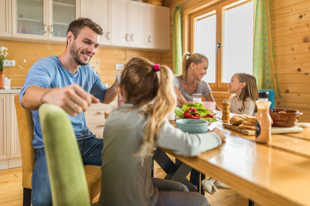 istock Young happy parents sitting with their daughters at dining table and communicating. 969442236