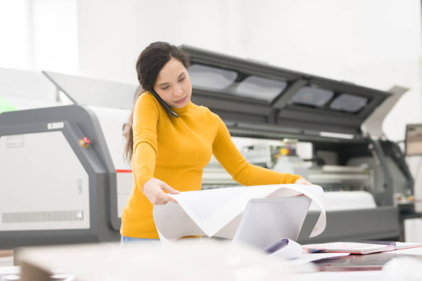 istock Serious concentrated busy mixed race female manager analyzing quality of print while talking on mobile phone in modern publishing company 969442296