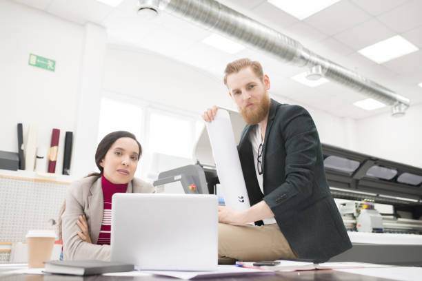 istock Content confident staff of printing house working as team and editing text before print, young multiethnic colleagues looking at camera in printing house 969442470