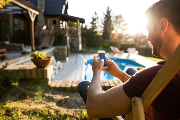 istock Relaxed man using smart phone in deck chair at the back yard. 969442588