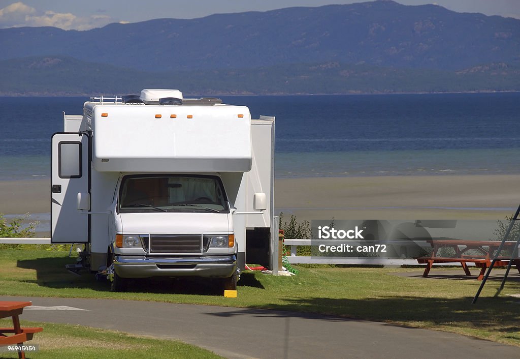 Campervan parked by the side of the sea An RV is parked alongside the Pacific Ocean at a beautiful campsite with the coastal mountains of British Columbia in the background. Beauty In Nature Stock Photo