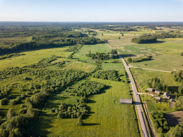 istock drone image. asphalt road surrounded by pine forest and fields from above 969458066