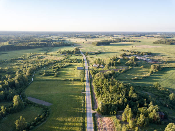 istock drone image. asphalt road surrounded by pine forest and fields from above 969461098