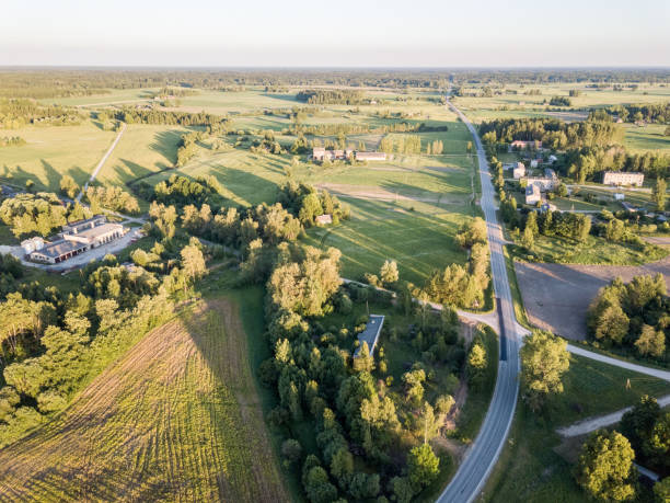 istock drone image. asphalt road surrounded by pine forest and fields from above 969461358