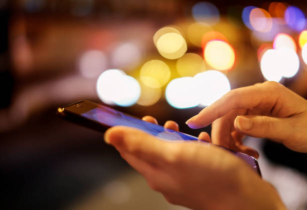istock Young woman using mobile phone with bokeh light at night city 969461836