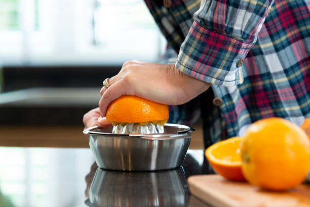 primer plano de manos de una mujer de exprimir naranjas para jugo - freshly squeezed fotografías e imágenes de stock