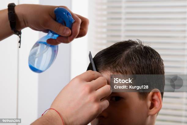 The Hairdresser To The Boy Moisturizes His Hair With A Spray Of Water And Makes A Hairdo Stock Photo - Download Image Now