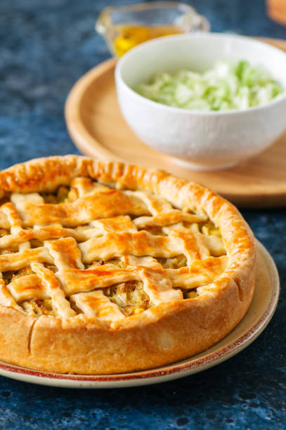istock Homemade young cabbage pie from flaky dough  served on a plate. Blue stone background. 969477154
