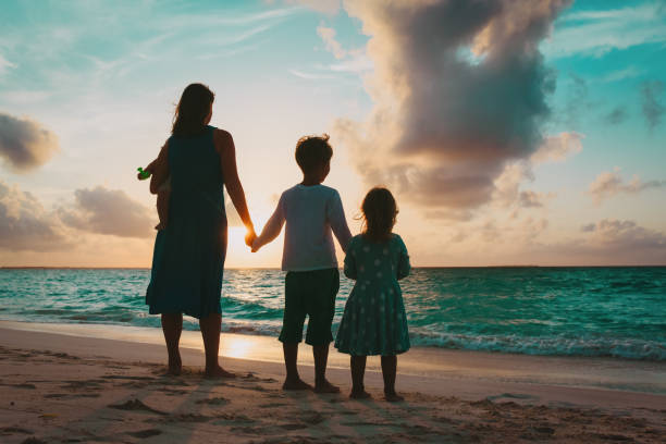 istock mother with kids looking at sunset on beach 969480978