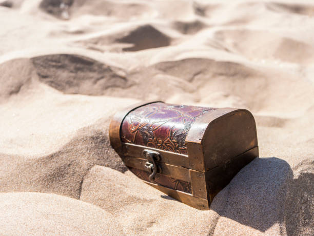 istock locked treasure case buried in sand on the beach 969484602
