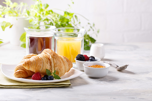 Breakfast served with croissants, coffee, orange juice and berries. Copy space.