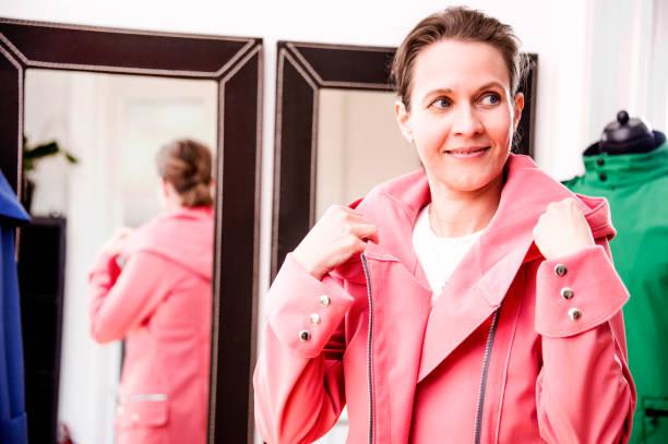 Young and pretty woman is fitting coats in a showroom. stock photo