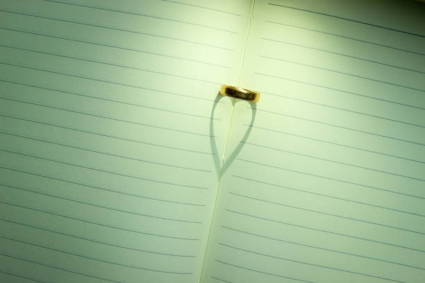 A Ring Shapes a Heart Shadow on An Open Notebook