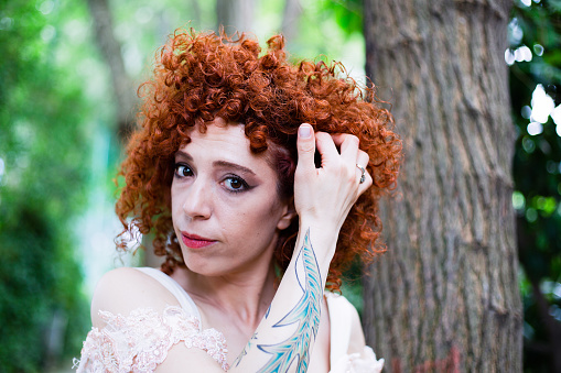 Redhead beautiful bride with curly hair and tattoo on her wedding day