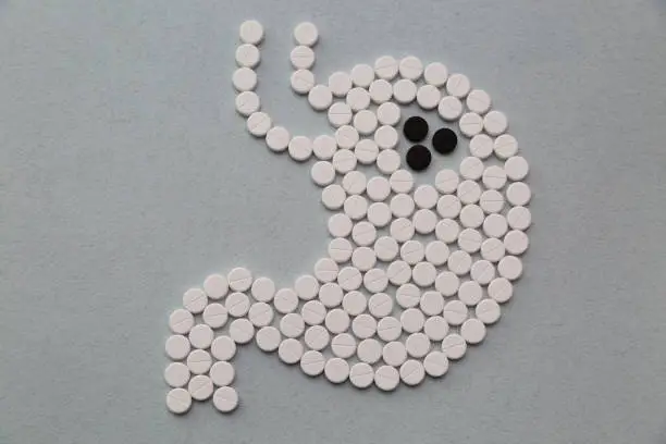 Photo of White and black pills in the shape of a stomach