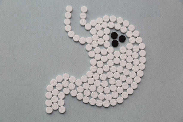 white and black pills in the shape of a stomach - cancro gástrico imagens e fotografias de stock