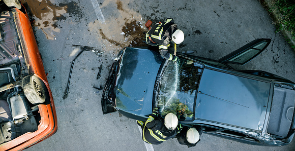 Firefighters using a glass cutter to cut car windscreen after accident.