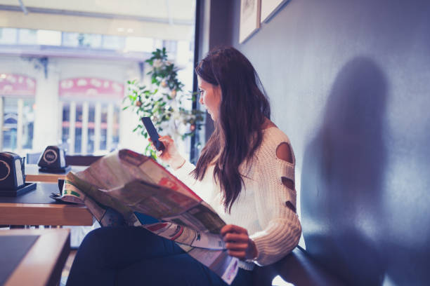 istock Young woman reading newspapers at cafe 969500758