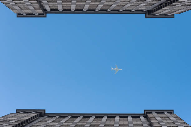 istock Airplanes leaves trace on clear blue sky between the two buildings. bottom view 969504176