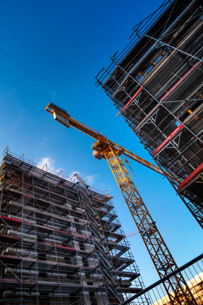 Hamburg - Germany, June 03. 2018: Construction site in a commercial area in Hamburg, Germany. Close up of a crane between two new buildings. The picture is taken upright. blue sky in the background. No people in this image