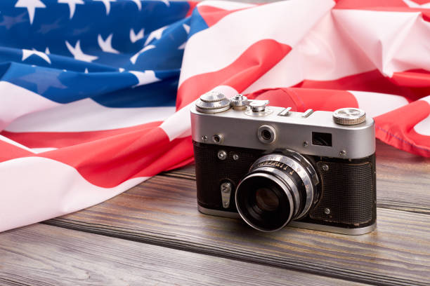 Retro camera and USA flag. Old film camera and American flag on wooden background close up.