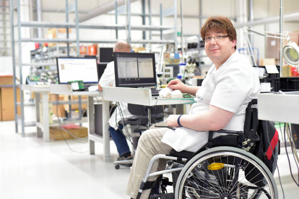 behinderte arbeitnehmer in einem rollstuhl, montage von elektronischen komponenten in einer modernen fabrik am arbeitsplatz - working physical impairment people occupation stock-fotos und bilder