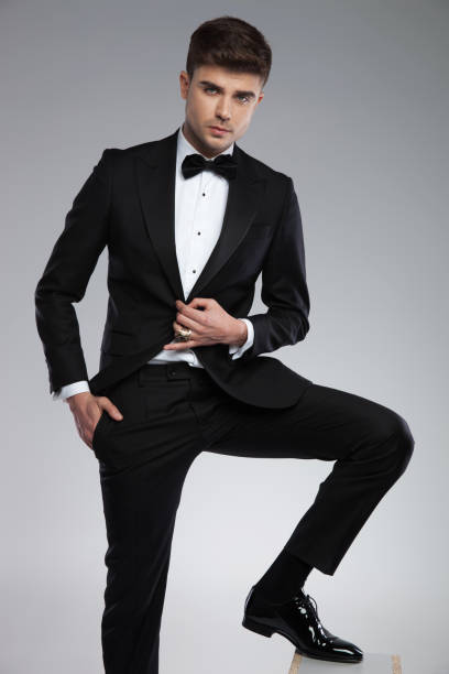 istock attractive young man wearing a black tuxedo posing relaxed 969519156