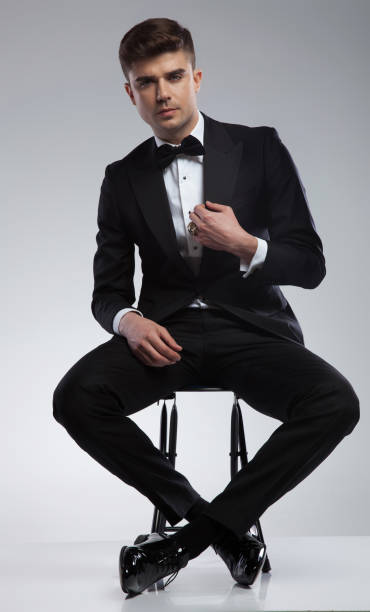 istock sexy seated elegant man fixing black suit collar 969519206
