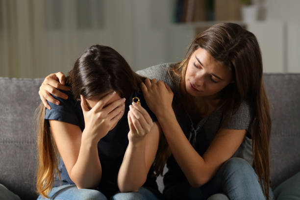 Girl comforting her divorced friend Girl comforting her divorced friend sitting on a couch in the living room at home woman comforting depressed friend stock pictures, royalty-free photos & images