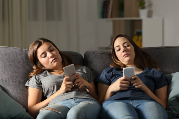 Bored friends using their smart phones Bored friends using their smart phones sitting on a couch in the living room at home boredom stock pictures, royalty-free photos & images
