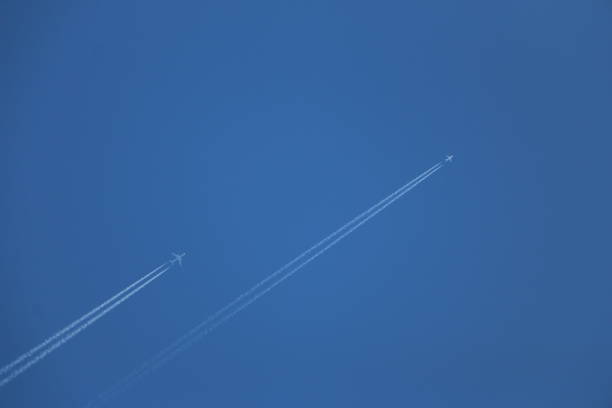istock two jet planes fly in a clear blue sky, leaving a white trail. two aircraft leave condensation traces in a clear blue sky 969539502