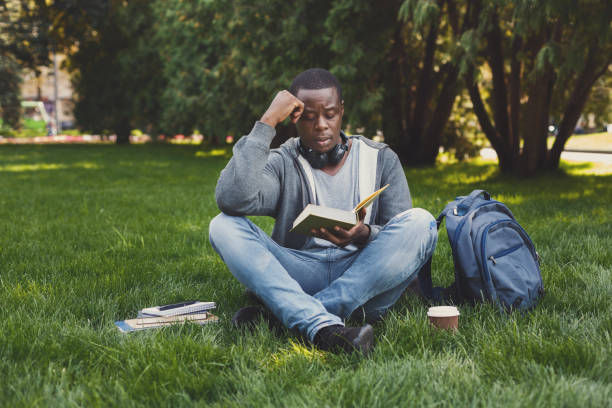 istock Young man reading book in park copy space 969543120