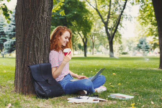 istock Happy young woman using laptop in park 969543410